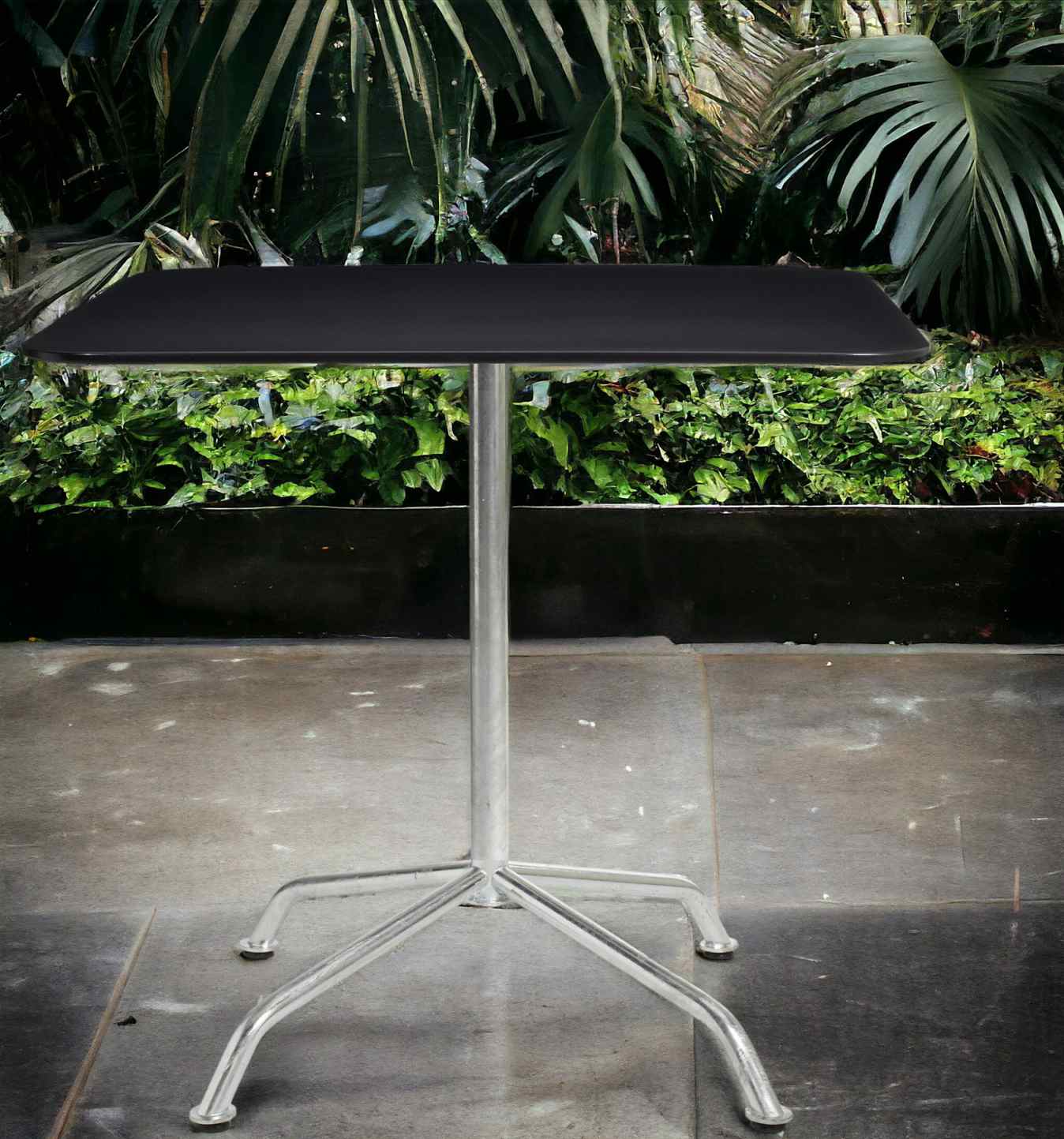 Schwarzer Haefeli Gartentisch mit silberfarbenem Gestell vor grünem Hintergrund. Outdoor Tisch für Garten und Terrasse.