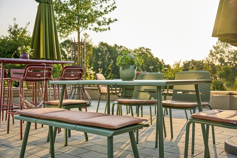 Weishäupl Vapio Sessel und Gartenmöbel-Set in Grün und Rot auf einer Terrasse im Freien.