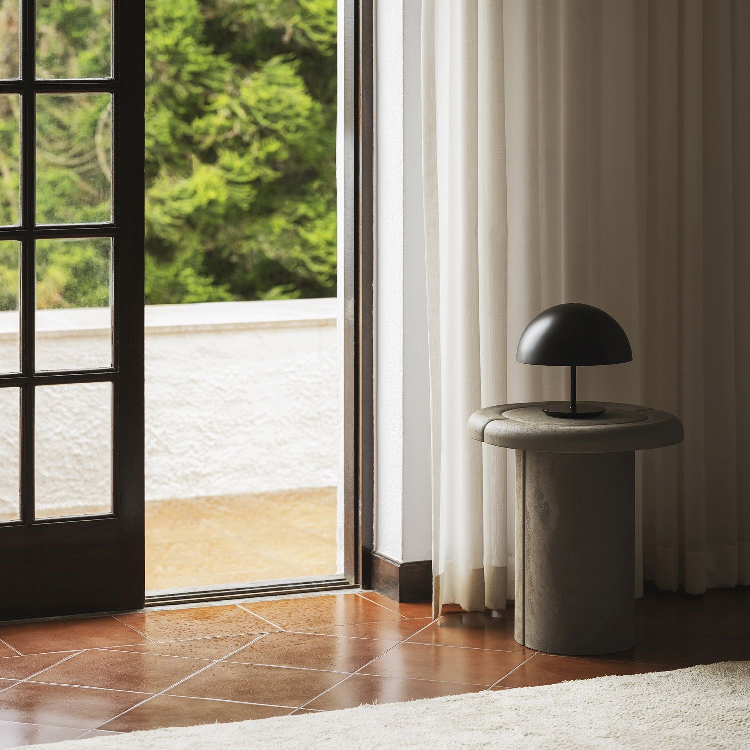 Alder Side Table Beistelltisch von Mater im Innenraum mit Lampe und geöffneter Tür zum Außenbereich.