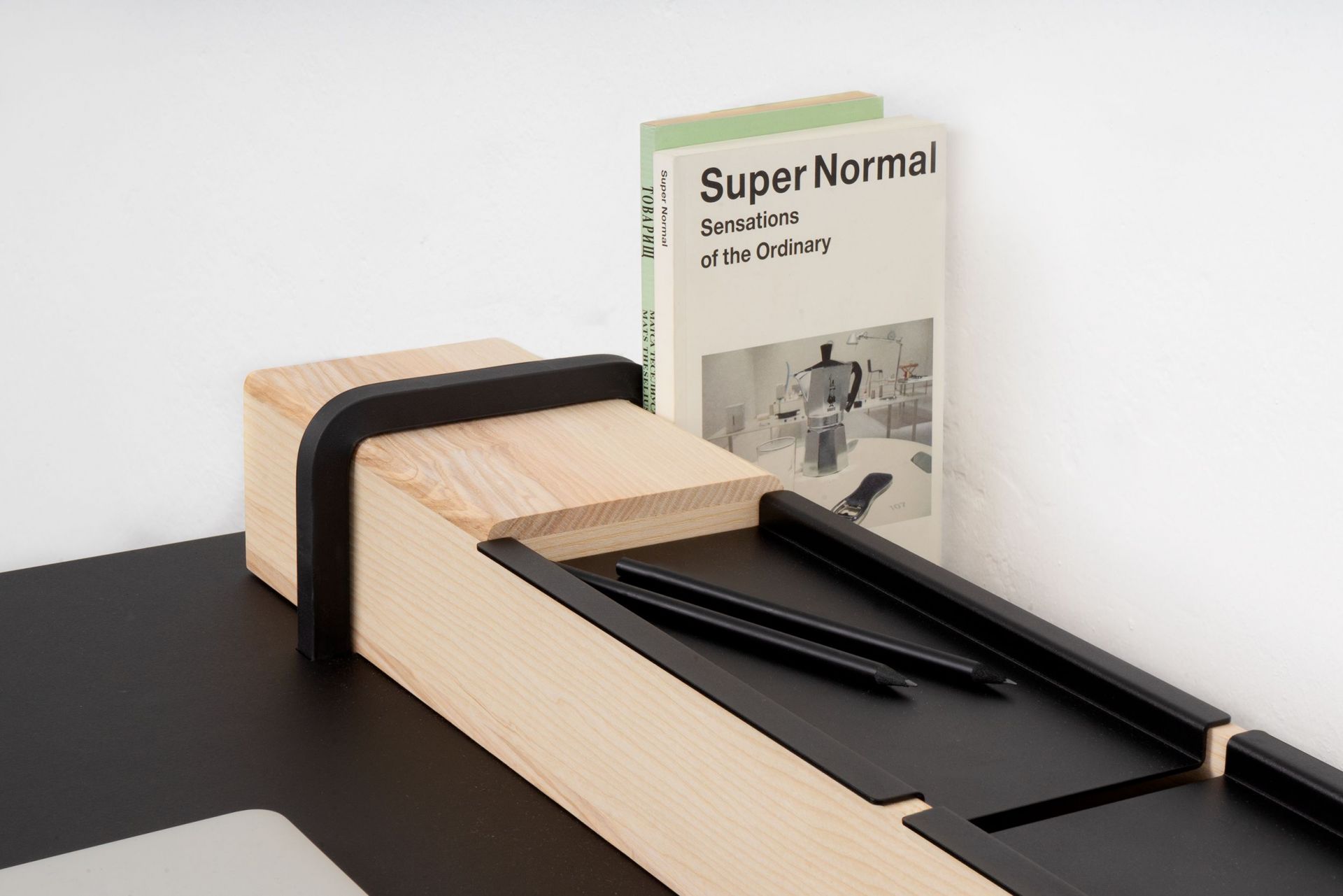 Detailaufnahme des Kurt Sekretärs von Moormann: Holz, schwarze Details, Bücher und Stifte.