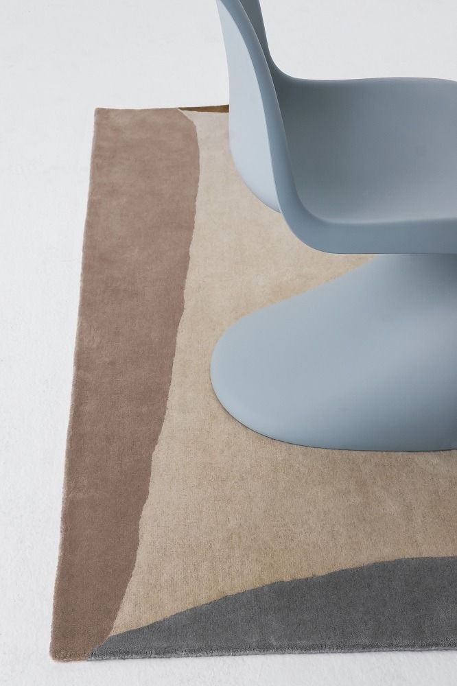Nanimarquina Teppich Tones Collection mit Farbverlauf und einem hellblauen Stuhl auf hellem Untergrund.
