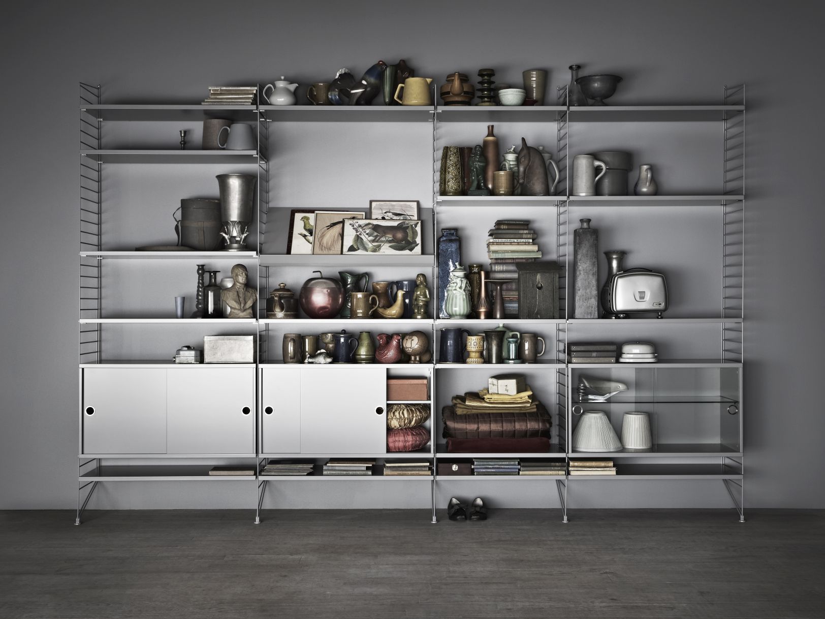 Vollständig bestücktes String Regalsystem in Walnuss und Schwarz, mit Schränken und Deko-Objekten.