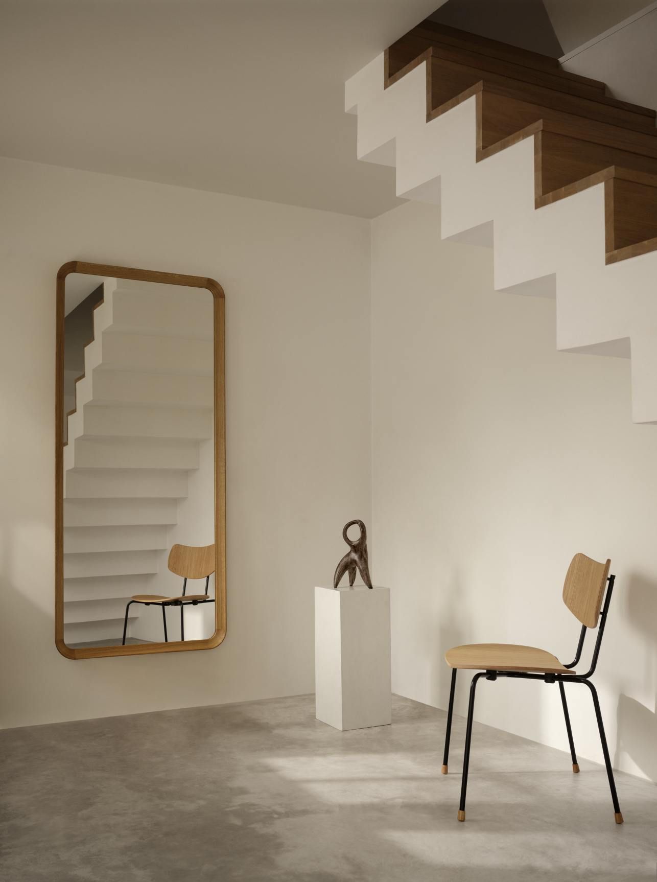 VLA62 Radio House Mirror von Carl Hansen & Søn in minimalistischem Interieur mit Treppe und Stuhl.