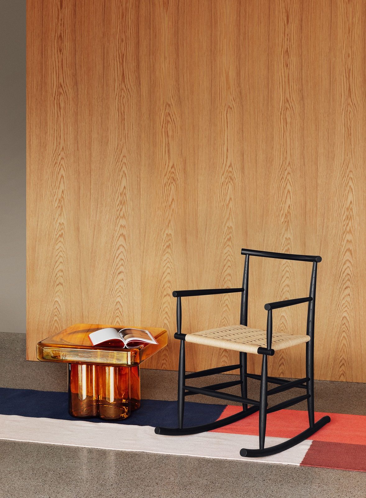 Soda Square Couchtisch von Miniforms mit Buch, neben einem schwarzen Schaukelstuhl auf einem Teppich.