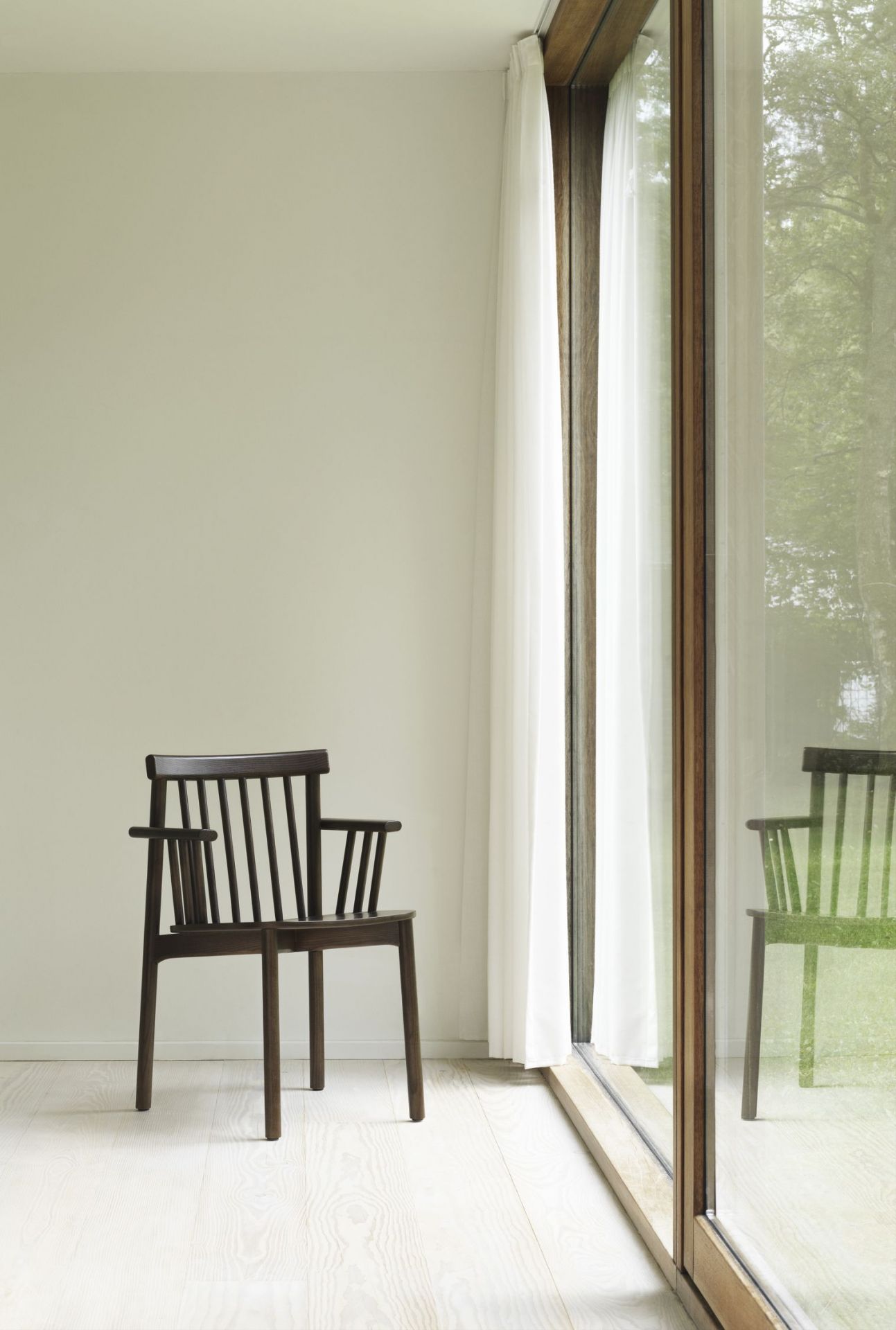 Dunkelbrauner Pind Armchair Armlehnenstuhl von Normann Copenhagen vor Fenster mit Vorhang. Design Stuhl für Wohnzimmer.
