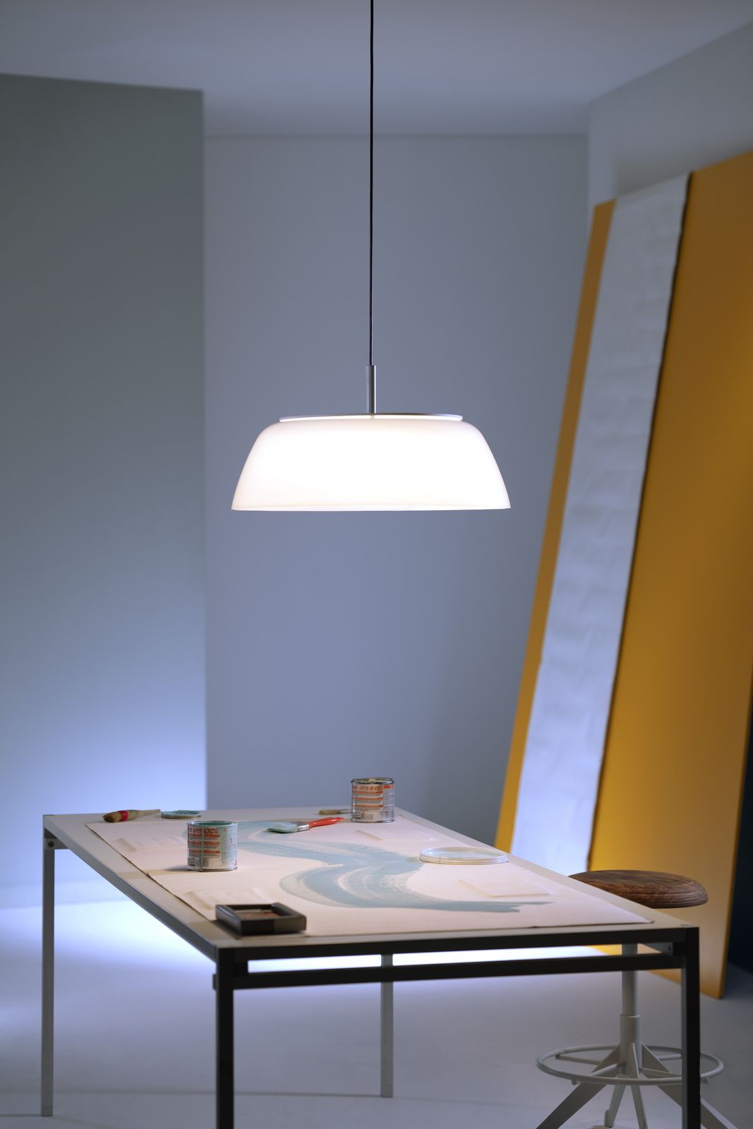 Weiße Onda Pendelleuchte von Martinelli Luce über einem Tisch mit Malutensilien.