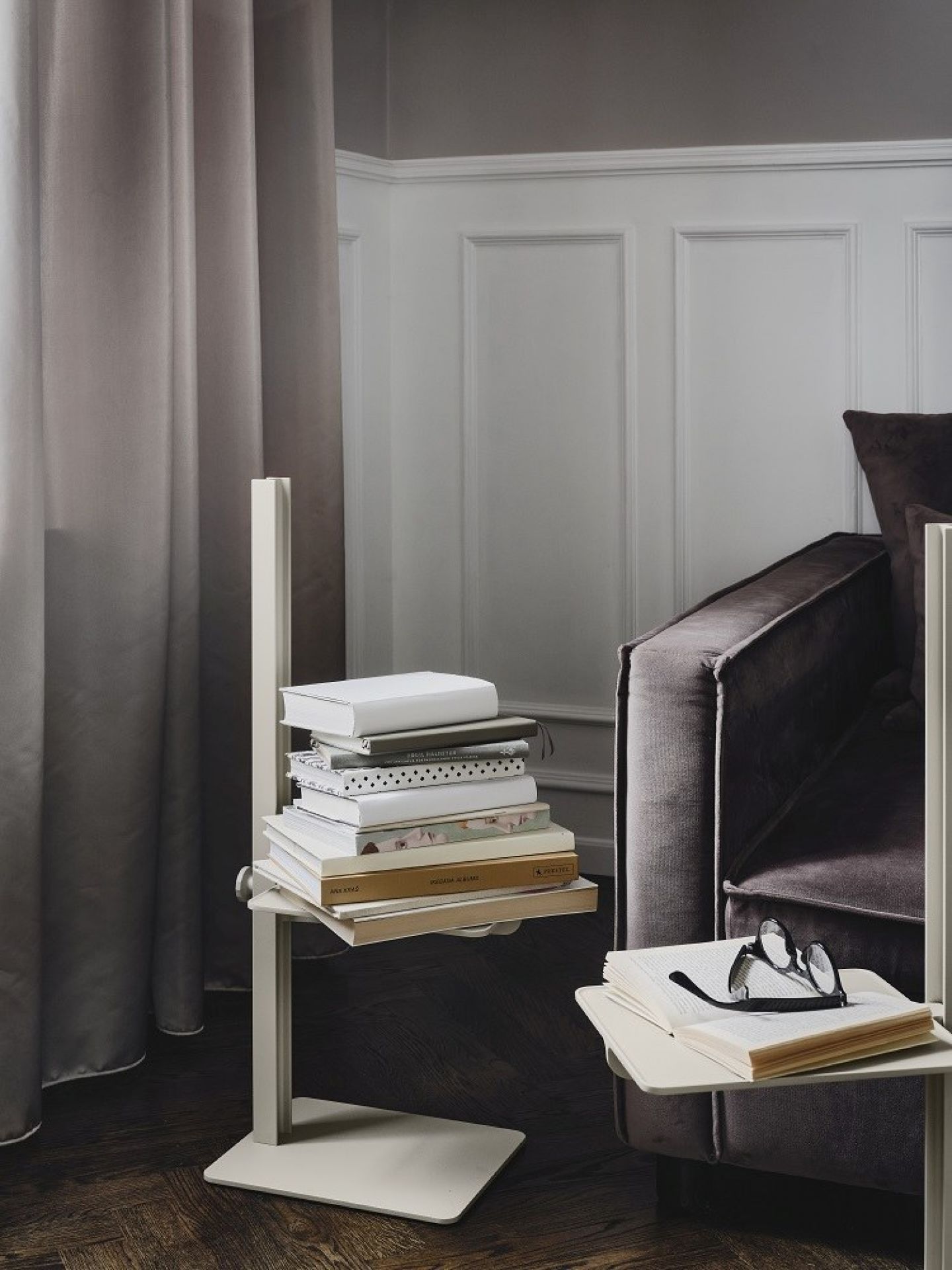 Beiger Museum Sidetable Beistelltisch von String Furniture mit Büchern, höhenverstellbar, neben einem Sofa.