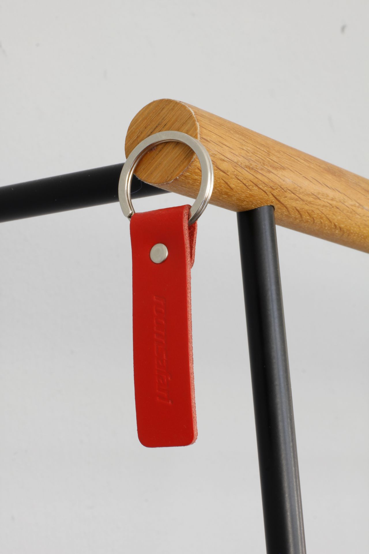 Detailaufnahme: Roomsafari Leanon II Anlehngarderobe, Nussbaum-Stange mit rotem Schlüsselanhänger. Garderoben-Möbel für Flur und Diele.