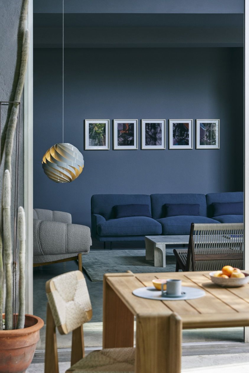 Helle Gubi Turbo Pendelleuchte im Wohnzimmer mit blauem Sofa und Holztisch, modernes skandinavisches Design.