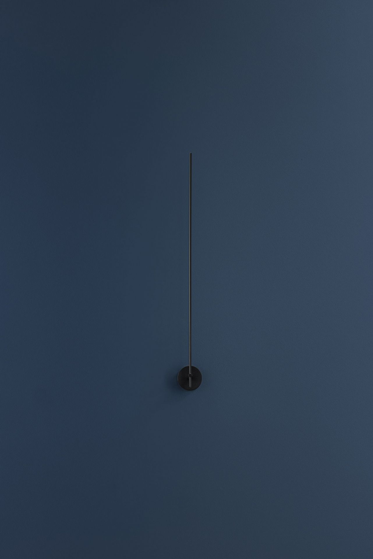 Schwarze Light Stick Wandleuchte von Catellani & Smith vor dunkelblauer Wand. Minimalistisches Design.