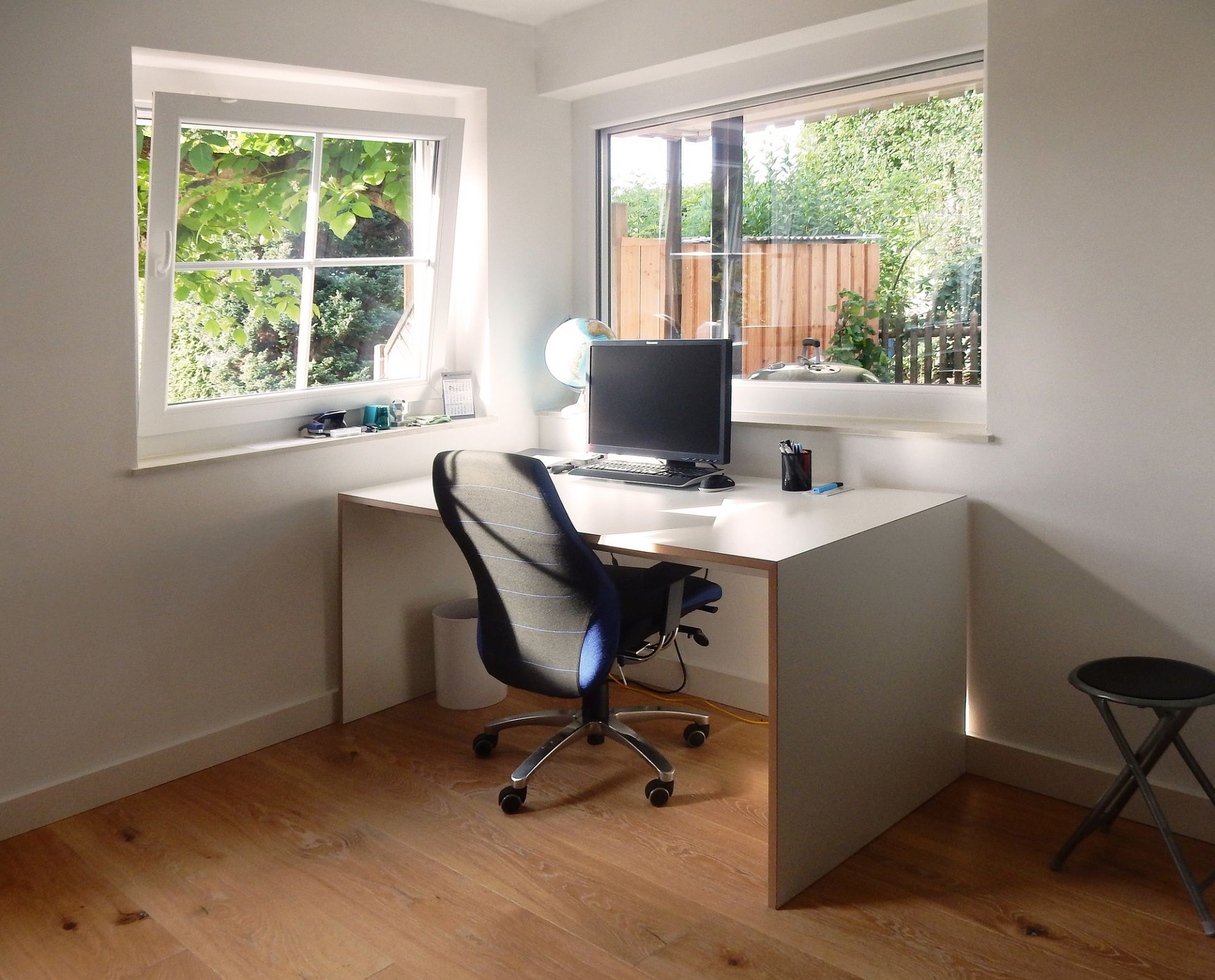 Heller Arbeitsplatz mit Tojo Schreibtisch, Bürostuhl, Computer und Fenster mit Blick ins Grüne.
