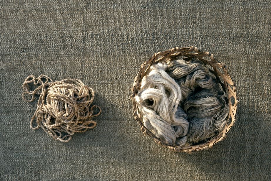 Detailaufnahme des Nanimarquina Vegetal Teppichs: Naturfasern und Wollknäuel in einem Korb auf dem Teppich.