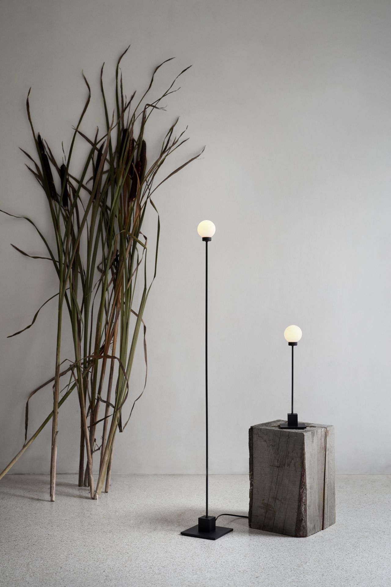 Weiße Snowball Tischleuchte von Northern, moderne LED Lampe mit schwarzem Fuß auf Holzwürfel.