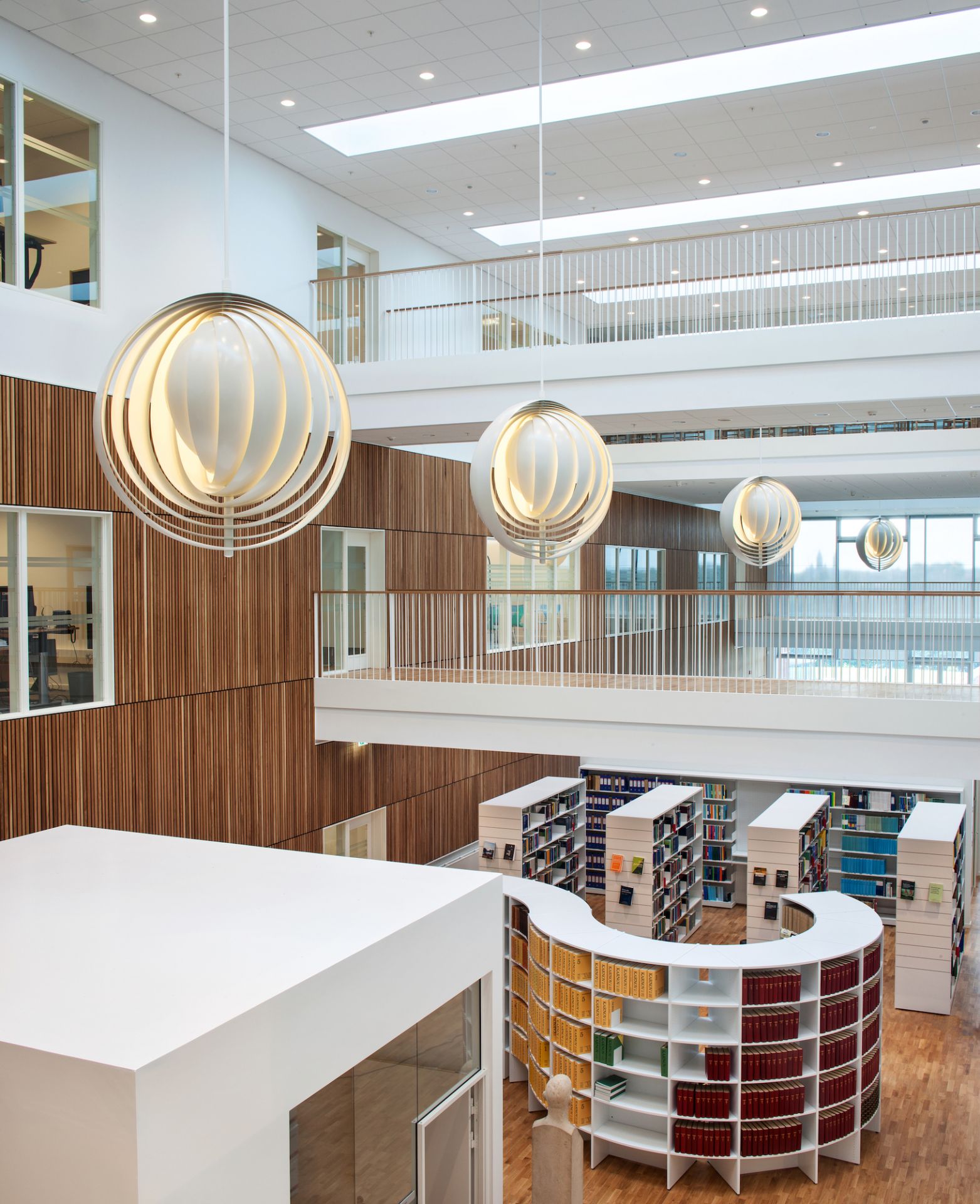 Innenaufnahme: Mehrere Verpan Moon Pendelleuchten in einer modernen Bibliothek. Designleuchte für stilvolle Raumbeleuchtung.