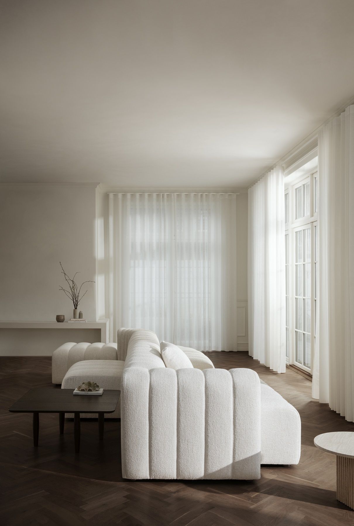 Nahaufnahme des NORR11 Soho Couchtisches aus dunklem Holz in einem hellen Wohnzimmer.