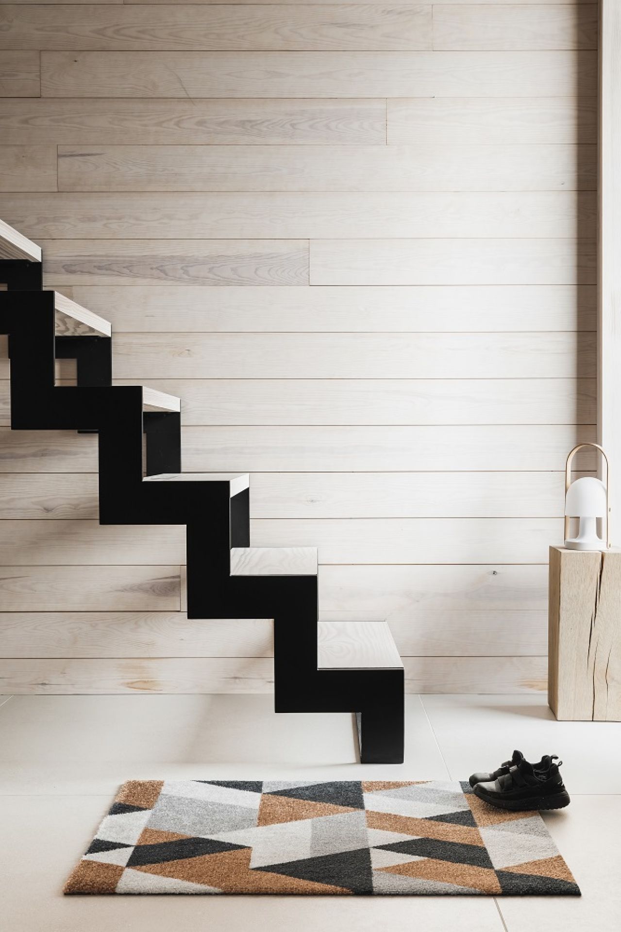 Blåne Heymat Fußmatte mit geometrischem Muster vor Treppe und Schuhen. Indoor/Outdoor Fußabtreter für den Eingangsbereich.