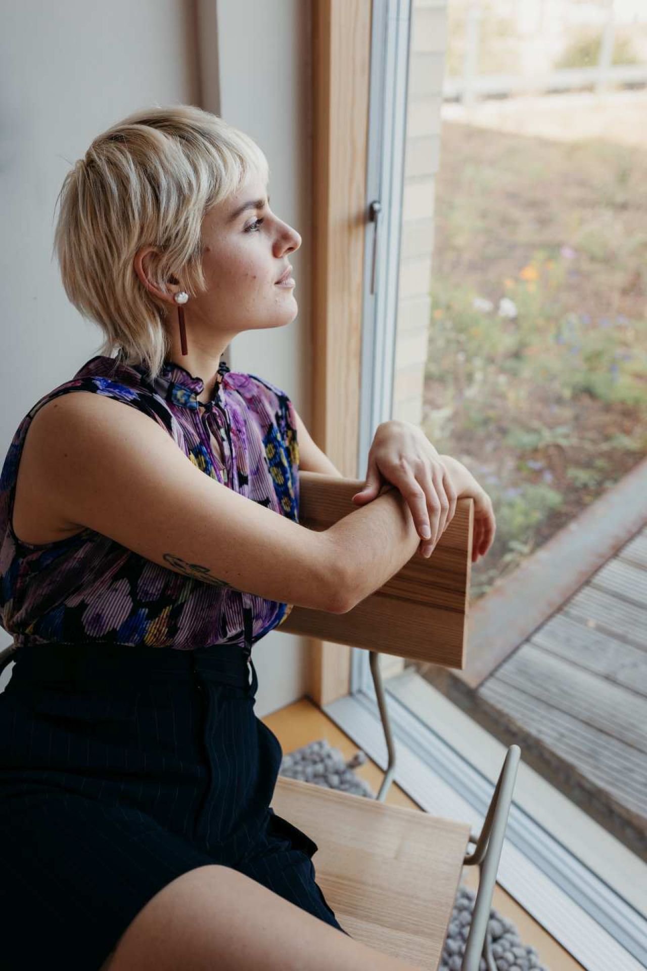 D:008 Loungechair: Frau sitzt entspannt im Sessel mit Armlehnen und blickt aus dem Fenster.
