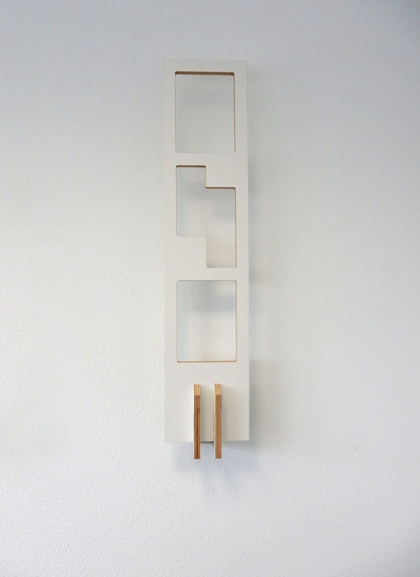 Weißes Tojo Lesestoff Bücherregal an der Wand mit drei Fächern und Holzdetails.