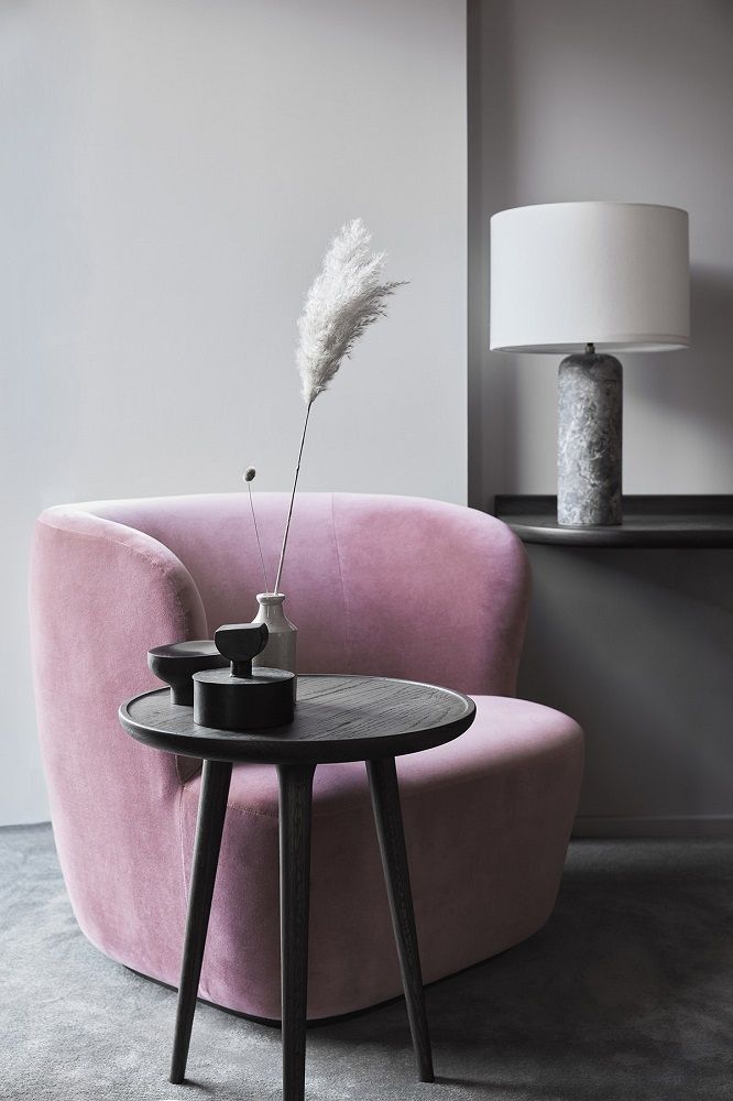 Eleganter Accent Beistelltisch aus Eiche, schwarz gebeizt, neben einem rosa Sessel. Dekorative Wohnaccessoires.