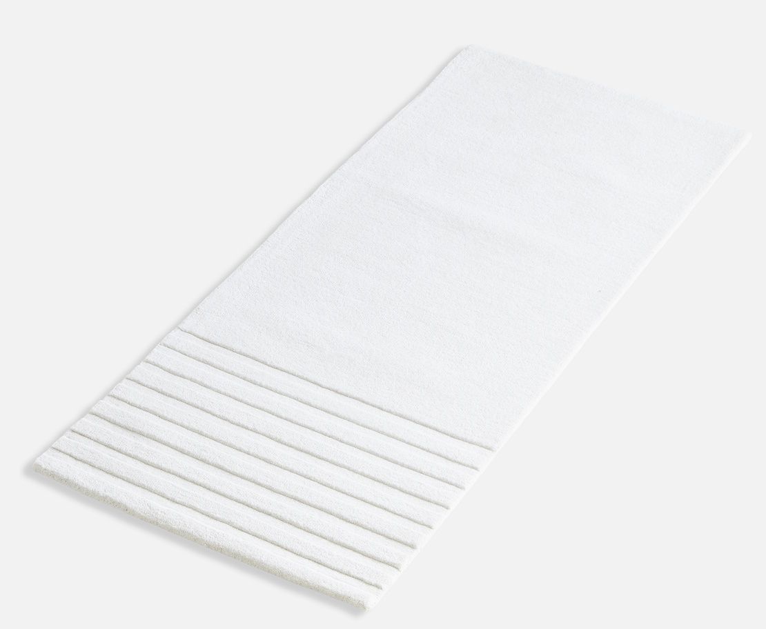 Weißer Kyoto Teppich von Woud (80x200 cm) mit gerippter Textur im unteren Bereich.