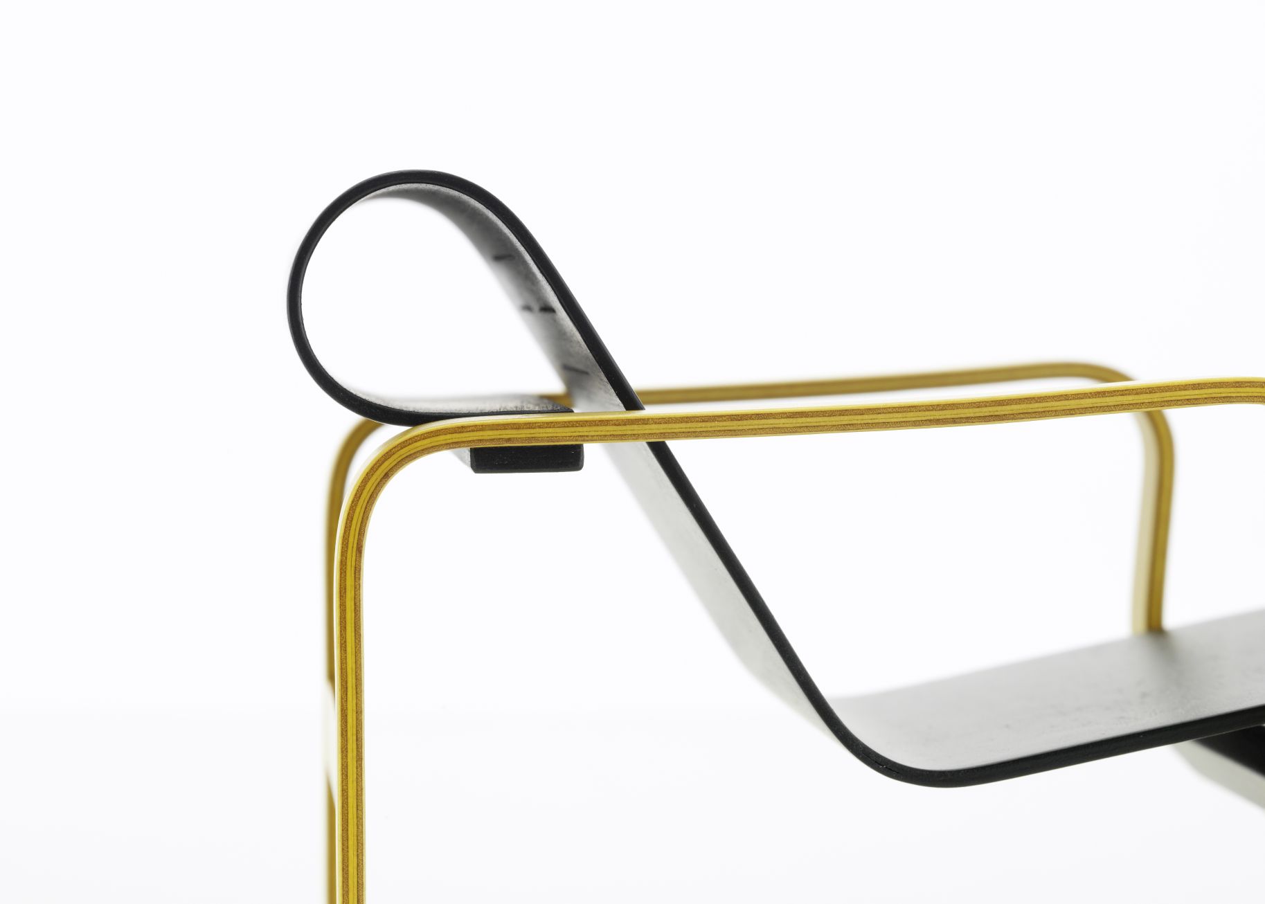 Detailaufnahme des Vitra Paimio Stuhls: Miniatur Designklassiker mit gelbem Holzrahmen und schwarzer Sitzfläche.