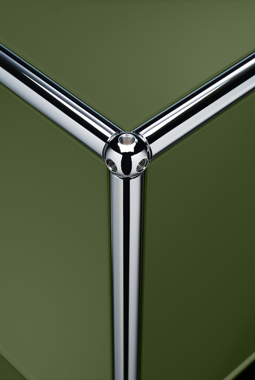 Detailaufnahme USM Haller Möbelbausystem: Olivgrüne Einschubtür und verchromtes Verbindungsrohr als Ersatzteil.