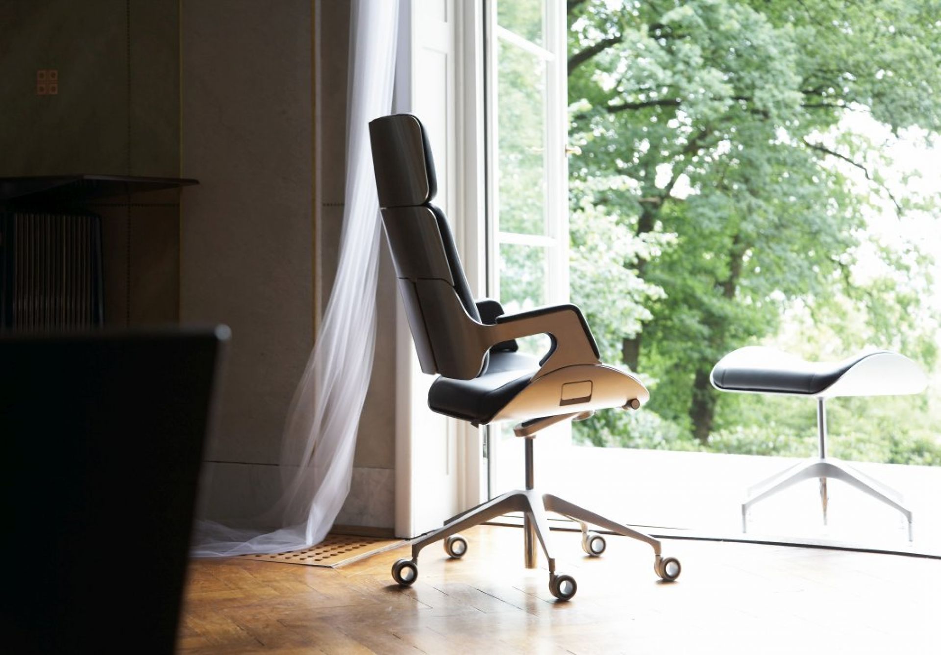 Silver Bürodrehstuhl von Interstuhl, hohe Rückenlehne, ergonomisch, mit Fußstütze vor Fenster. Moderner Bürostuhl.