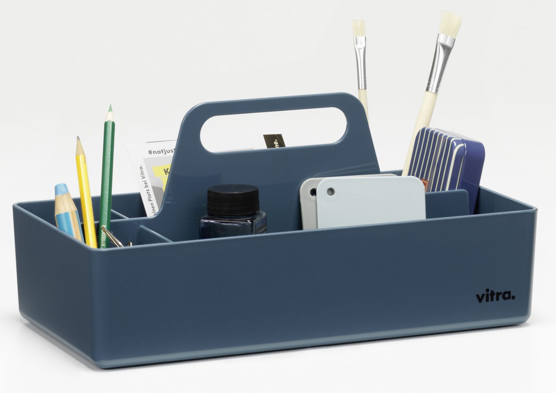 Vitra Toolbox RE, meerblaue Aufbewahrungsbox mit Griff und diversen Büro- und Malutensilien, ideal zur Organisation.