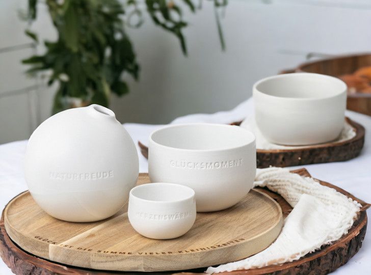 Tablett der kleinen Dinge mit weißen Keramikschalen und Vase mit den Aufschriften Naturfreude, Glücksmoment, Herzenswärme.