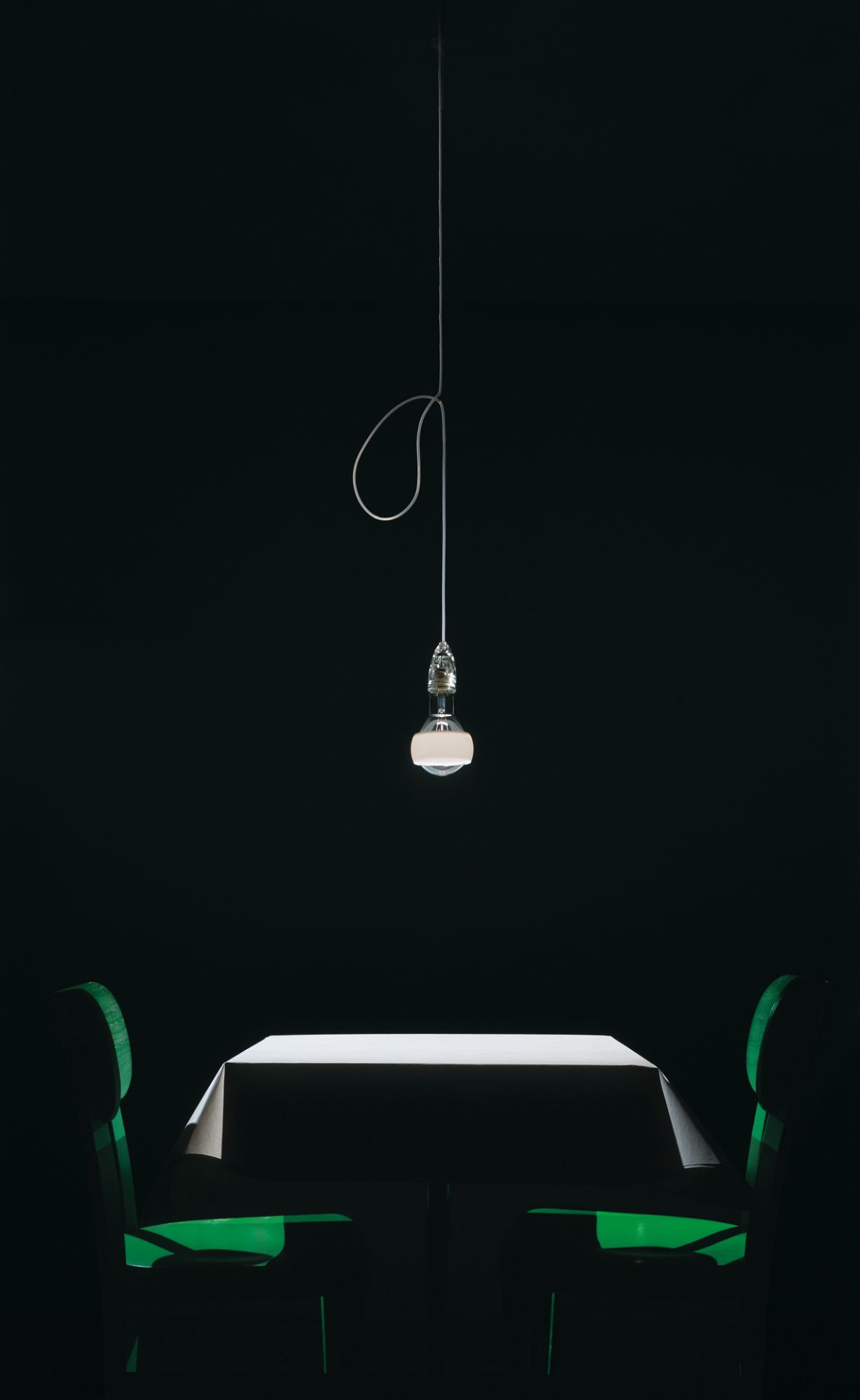 Johnny B. Good Lampe von Ingo Maurer über Esstisch mit grünen Stühlen.