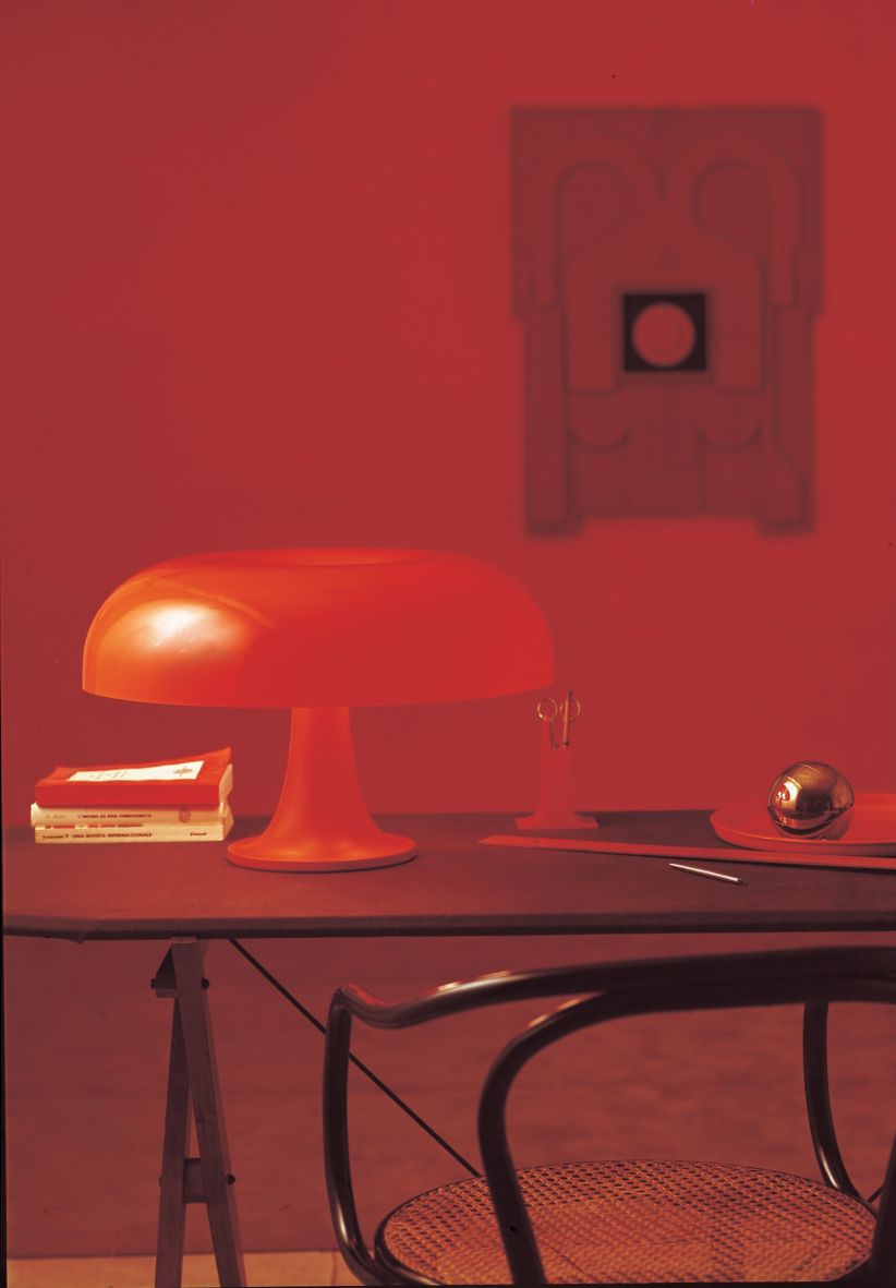 Orange Nesso Tischleuchte von Artemide auf einem Schreibtisch mit Accessoires, ikonisches Designobjekt.
