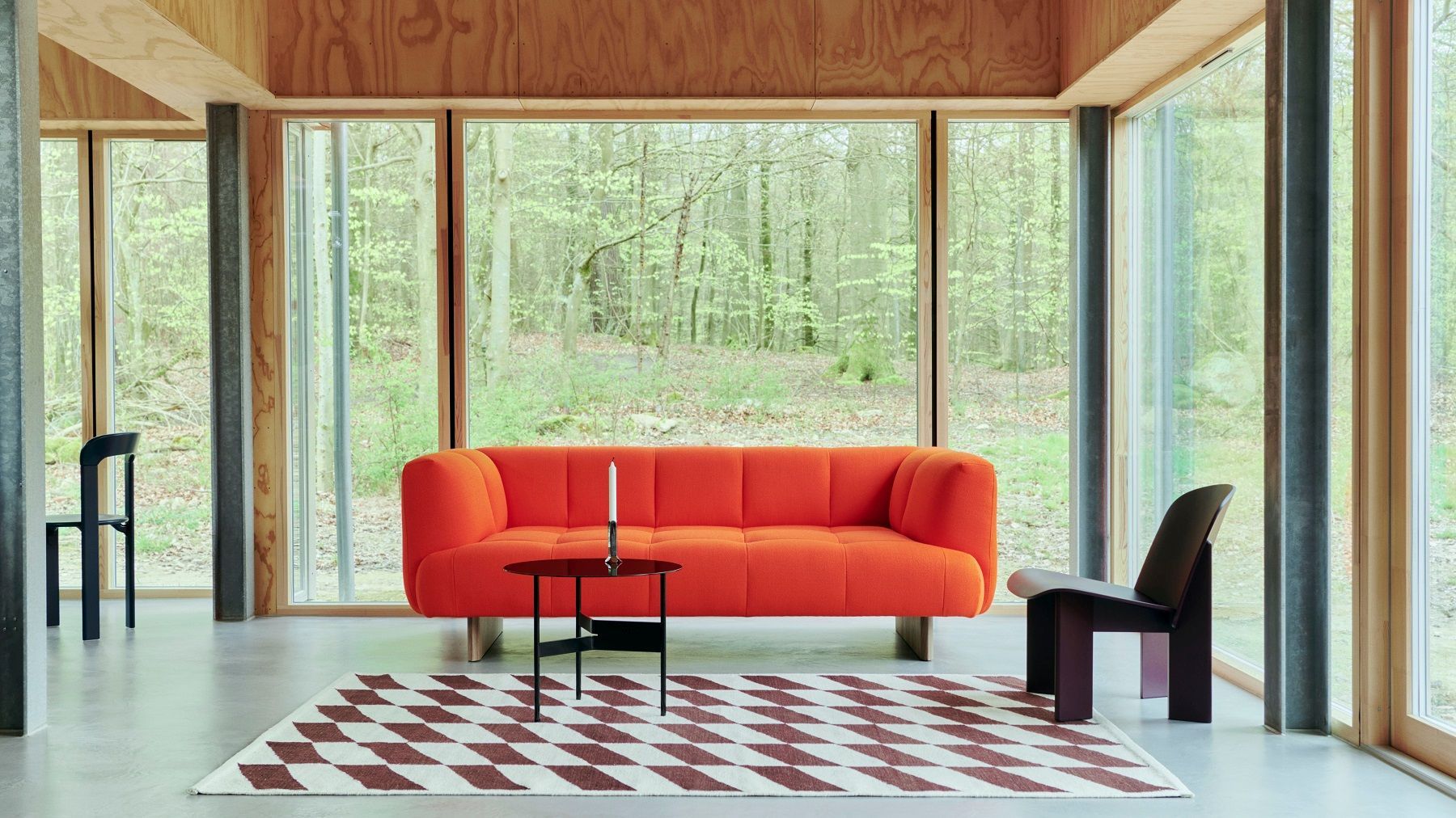 Wohnzimmer mit rotem Sofa, Schachbrett-Teppich und Hay Shim Table Couchtisch in Schwarz.