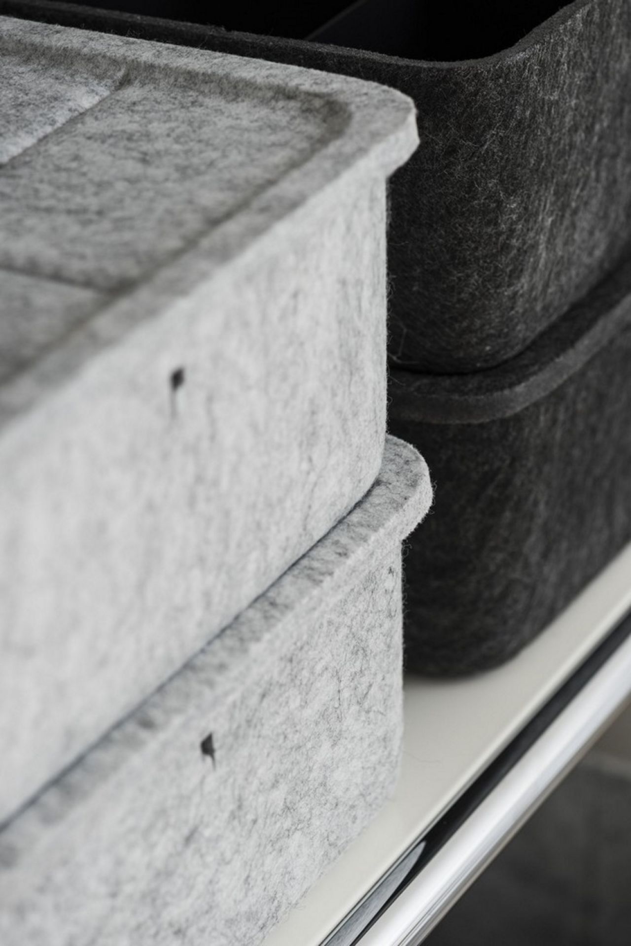Graue und schwarze USM Haller Inos Box tief aus Filz im Detail auf einem Regal.