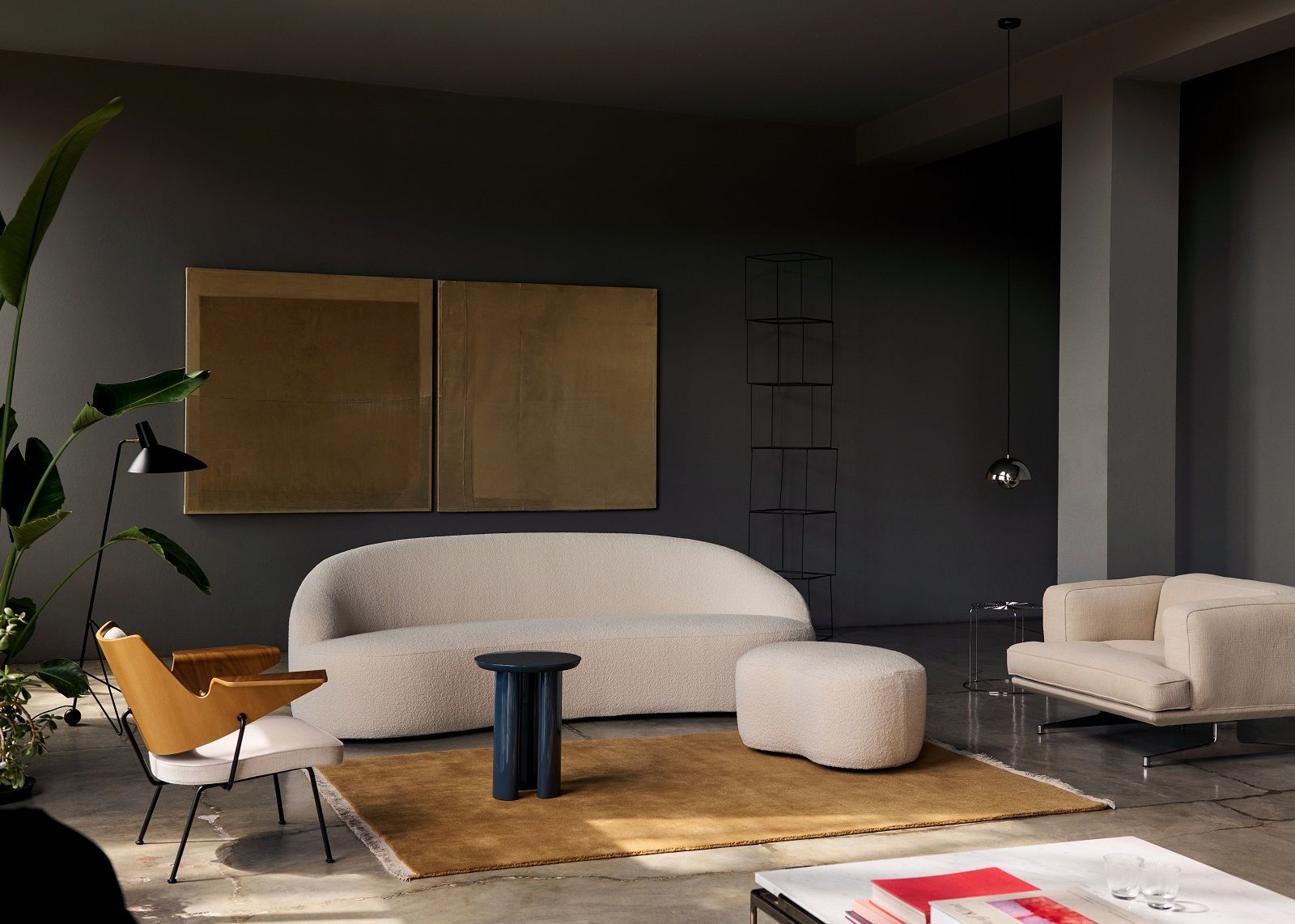 AndTradition Margas LC4 Sofa in Beige mit Sessel und Hocker in stilvollem Wohnzimmer.