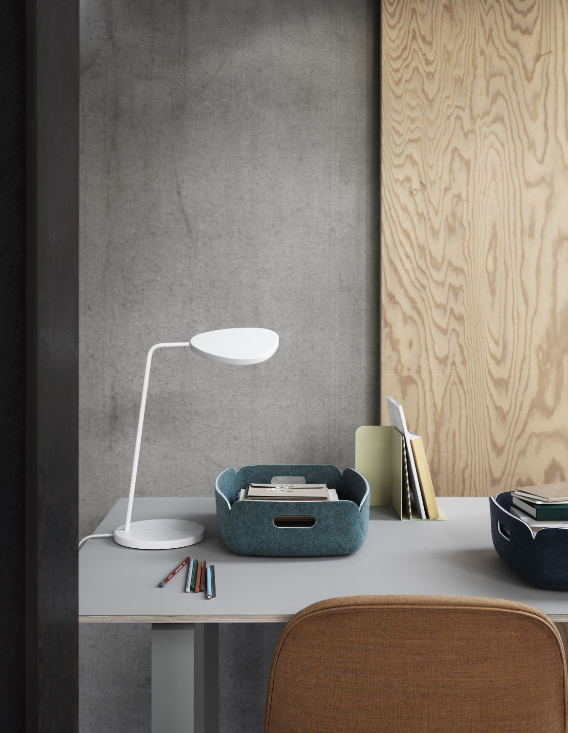 Muuto Restore Tray Basket in Staubgrün auf Schreibtisch mit Lampe und Büromaterial.
