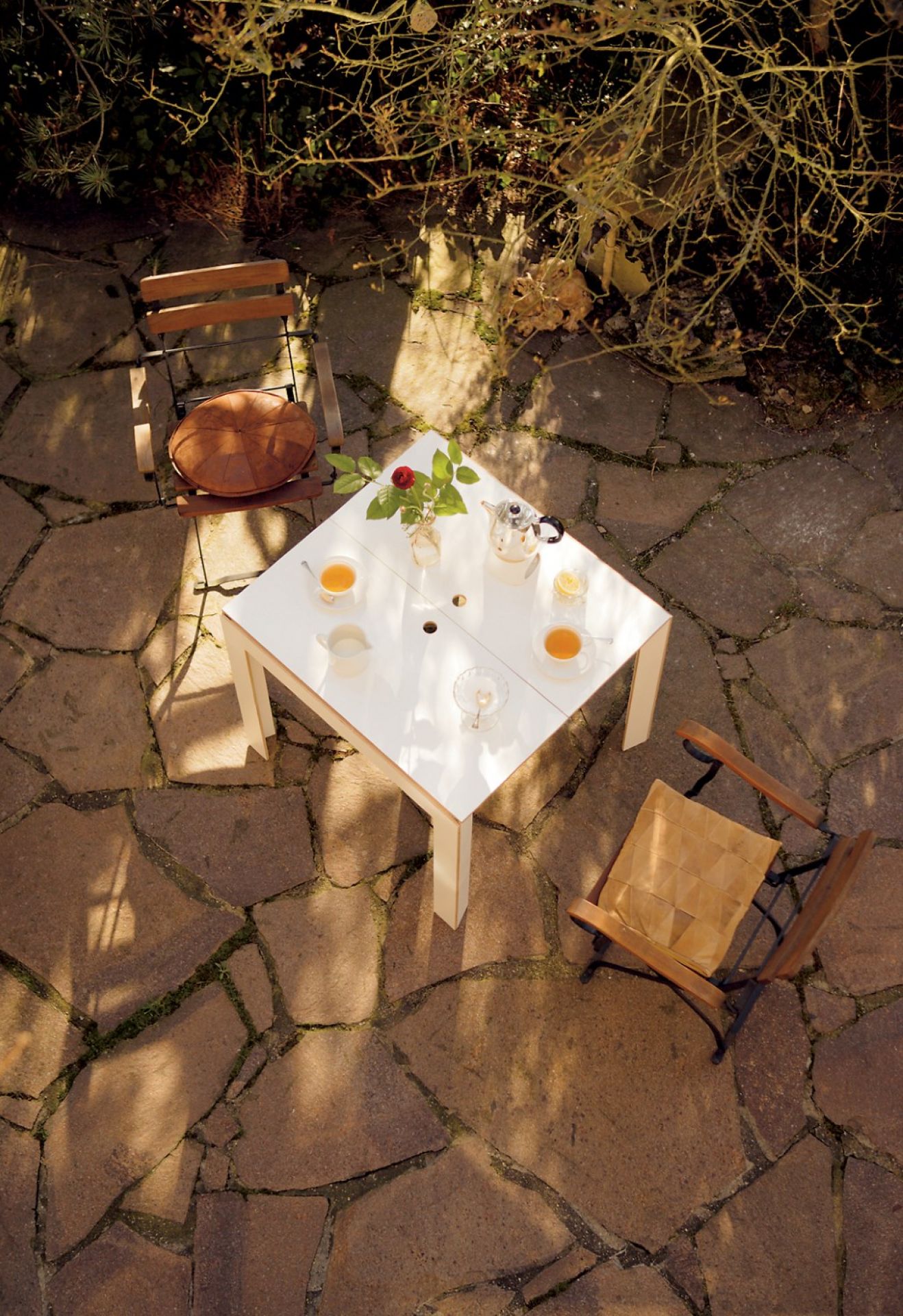 Draufsicht: Weißer Moormann Klapptisch mit Tee und zwei Stühlen im Garten.