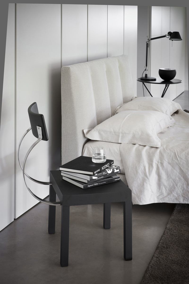 Follia Stuhl von Zanotta neben Bett mit Nachttisch und Büchern in modernem Schlafzimmer.