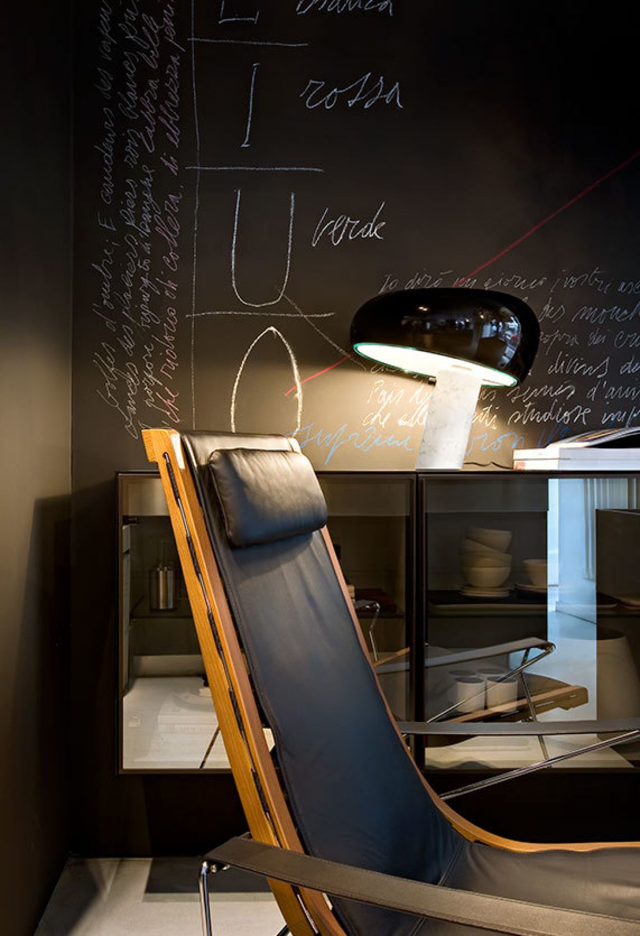 Schwarze Snoopy Tischleuchte von Flos auf einem Schrank, daneben ein Ledersessel. Design Lampe für Wohnzimmer.