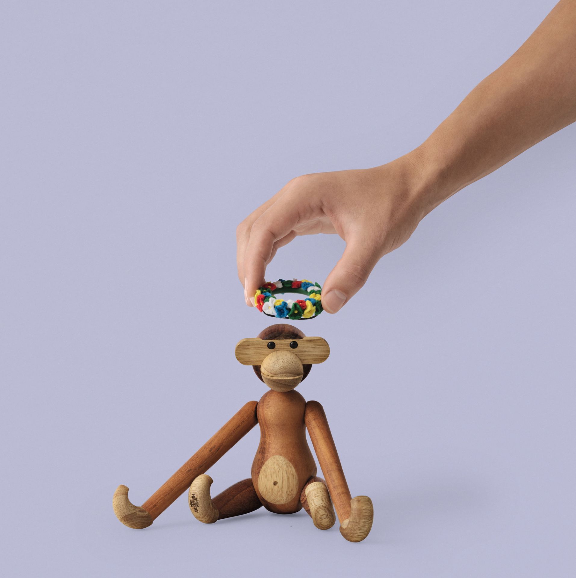 Hand hält Mittsommer Kranz über Kay Bojesen Affe Holzfigur. Dekoration für Holztiere.