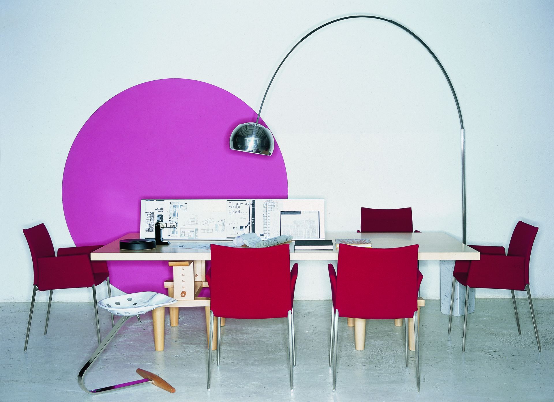 Rote Lia Stühle von Zanotta mit Armlehnen um einen hellen Esstisch. Designermöbel für Esszimmer.