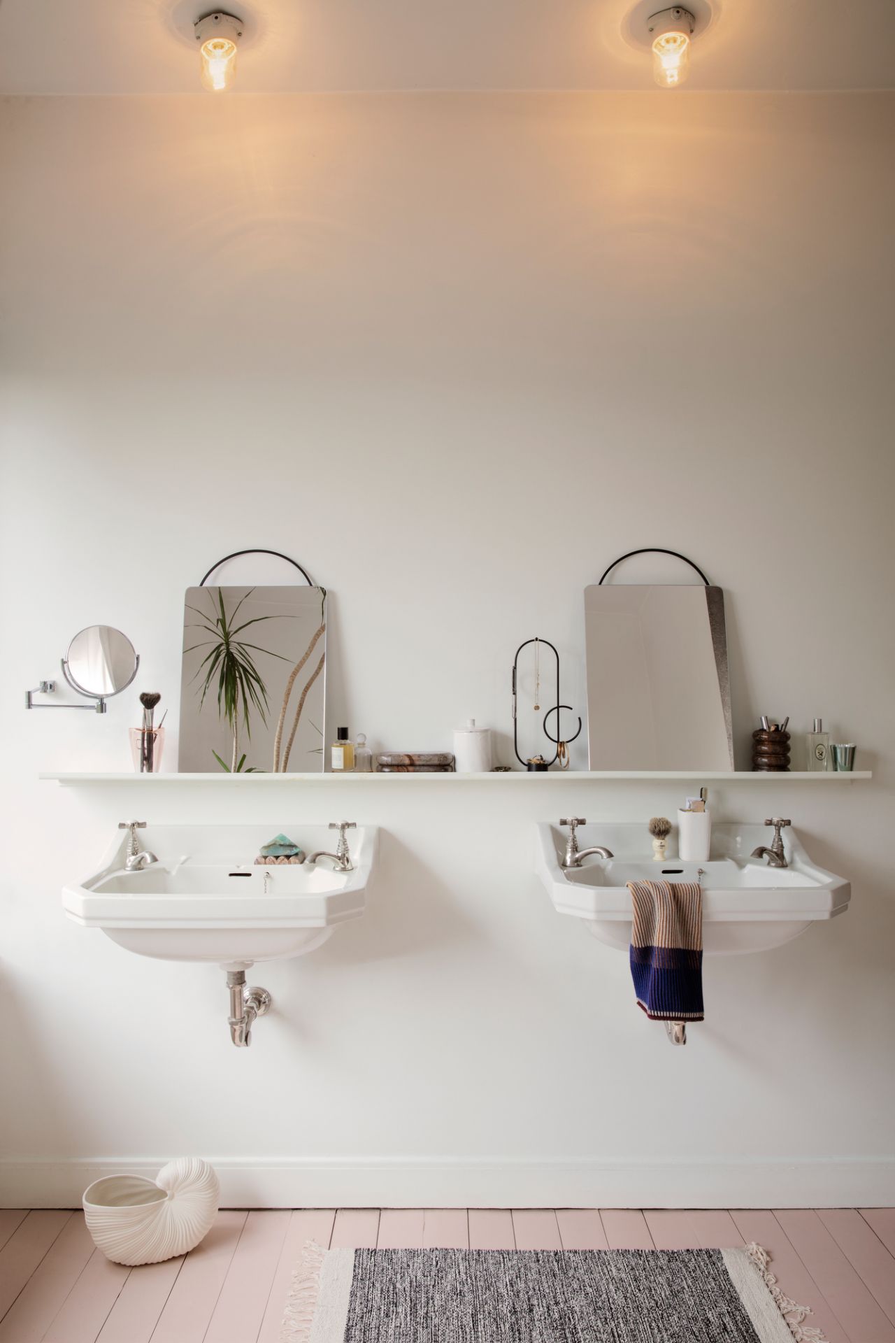 Badezimmer mit zwei Waschbecken, Spiegeln und einem Obu Jewellery Schmuckständer auf einem Regal.