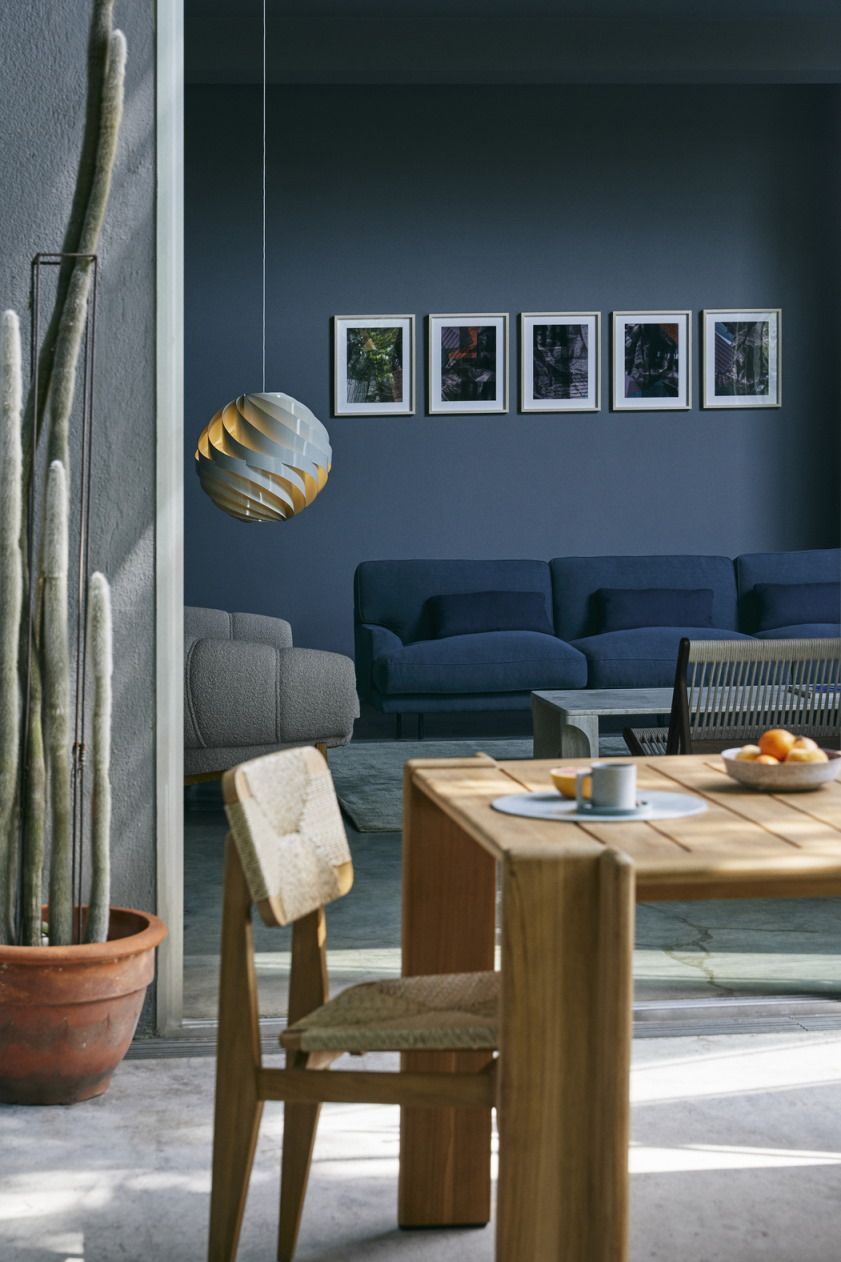 Helle Gubi Turbo Pendelleuchte im modernen Wohnzimmer mit Esstisch und blauer Couch. Design Lampe für stilvolle Innenarchitektur.