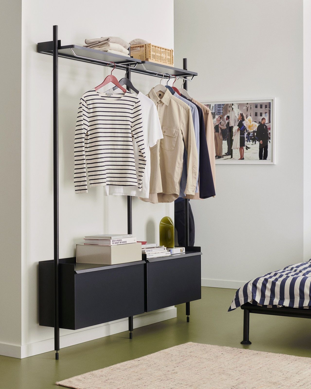 Hay Pier System Regal mit zwei Säulen, Garderobe mit Kleidung und Ablageflächen in einem Schlafzimmer.