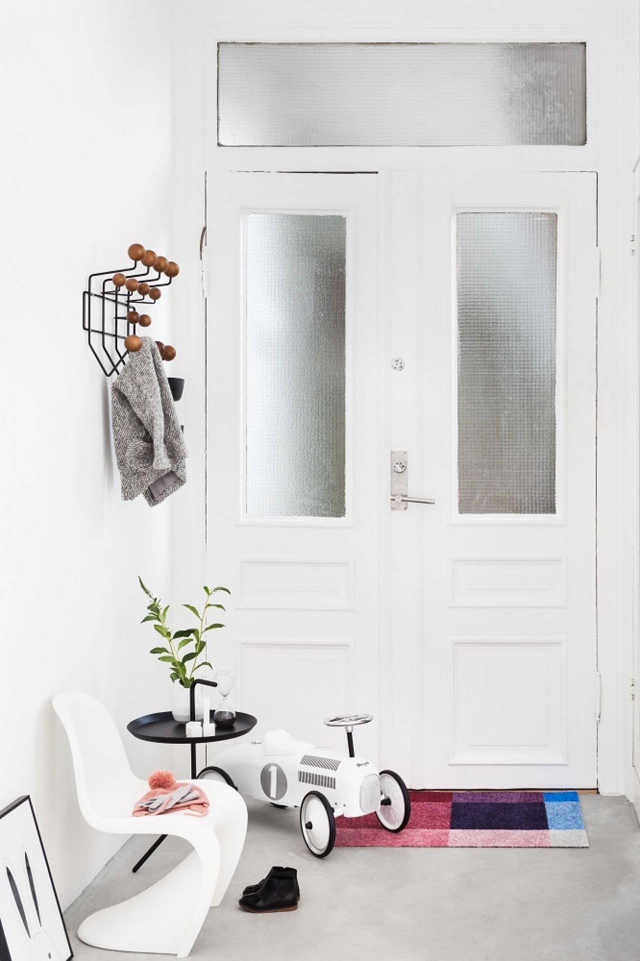 Eingangsbereich mit Heymat Fußmatte in bunten Farben, Kinderspielzeugauto und minimalistischer Einrichtung.