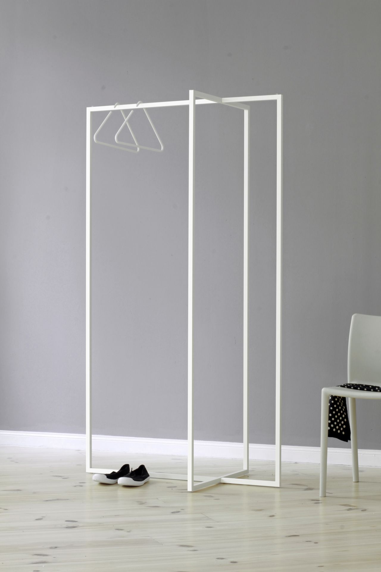 Roomsafari Modular Frames L Garderobe in Weiß mit Kleiderbügeln, Schuhen und Stuhl. Moderne Garderobenlösung.