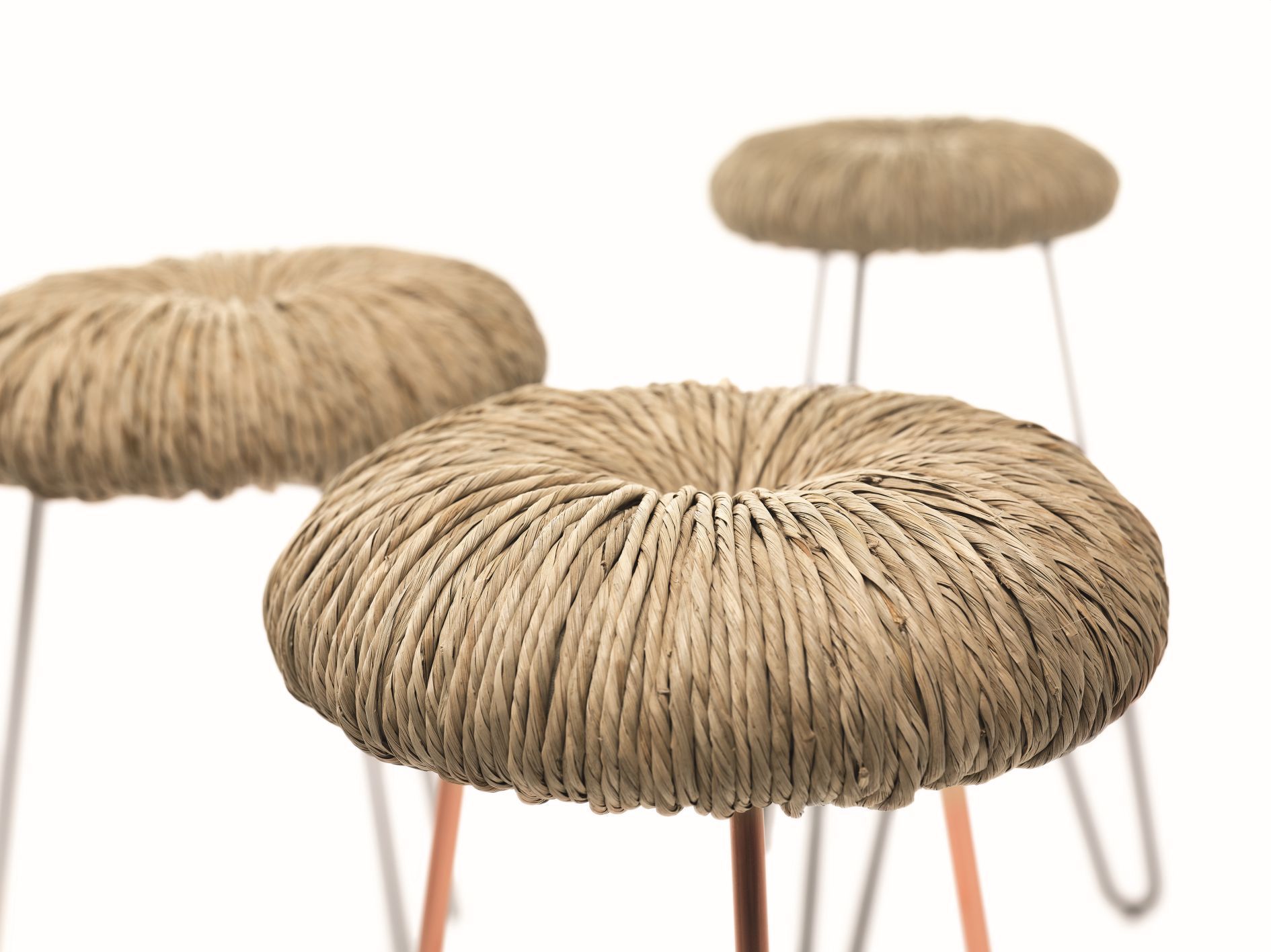 Bild von drei Donut Hockern mit hellem, geflochtenem Sitz und filigranen Metallbeinen.