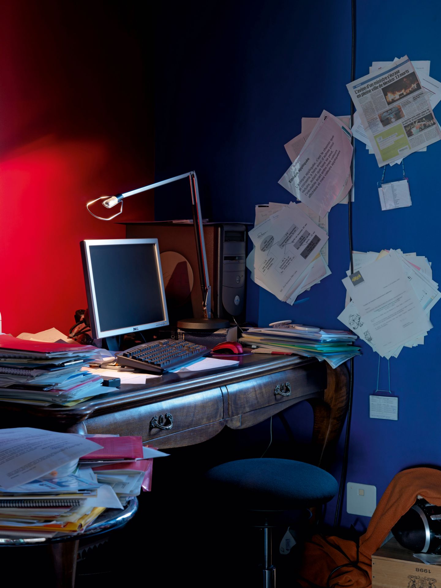 Detailaufnahme: Belux Lifto Tischleuchte mit Kugelgelenk-Adapter auf einem unordentlichen Schreibtisch.