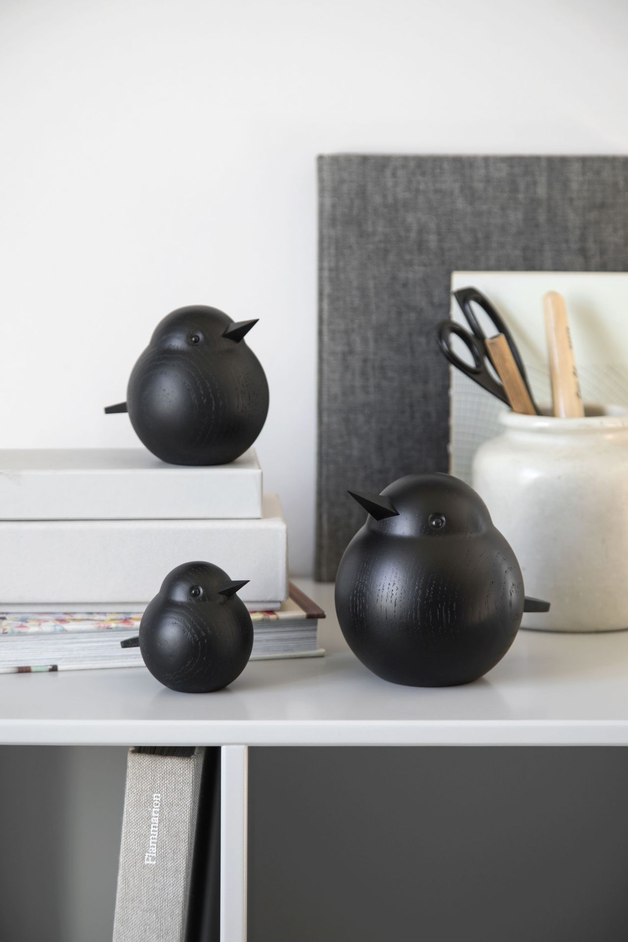 Drei schwarze Holzfiguren, Papa Sparrow von Novoform, als dekorative Wohnaccessoires auf einem Regal.