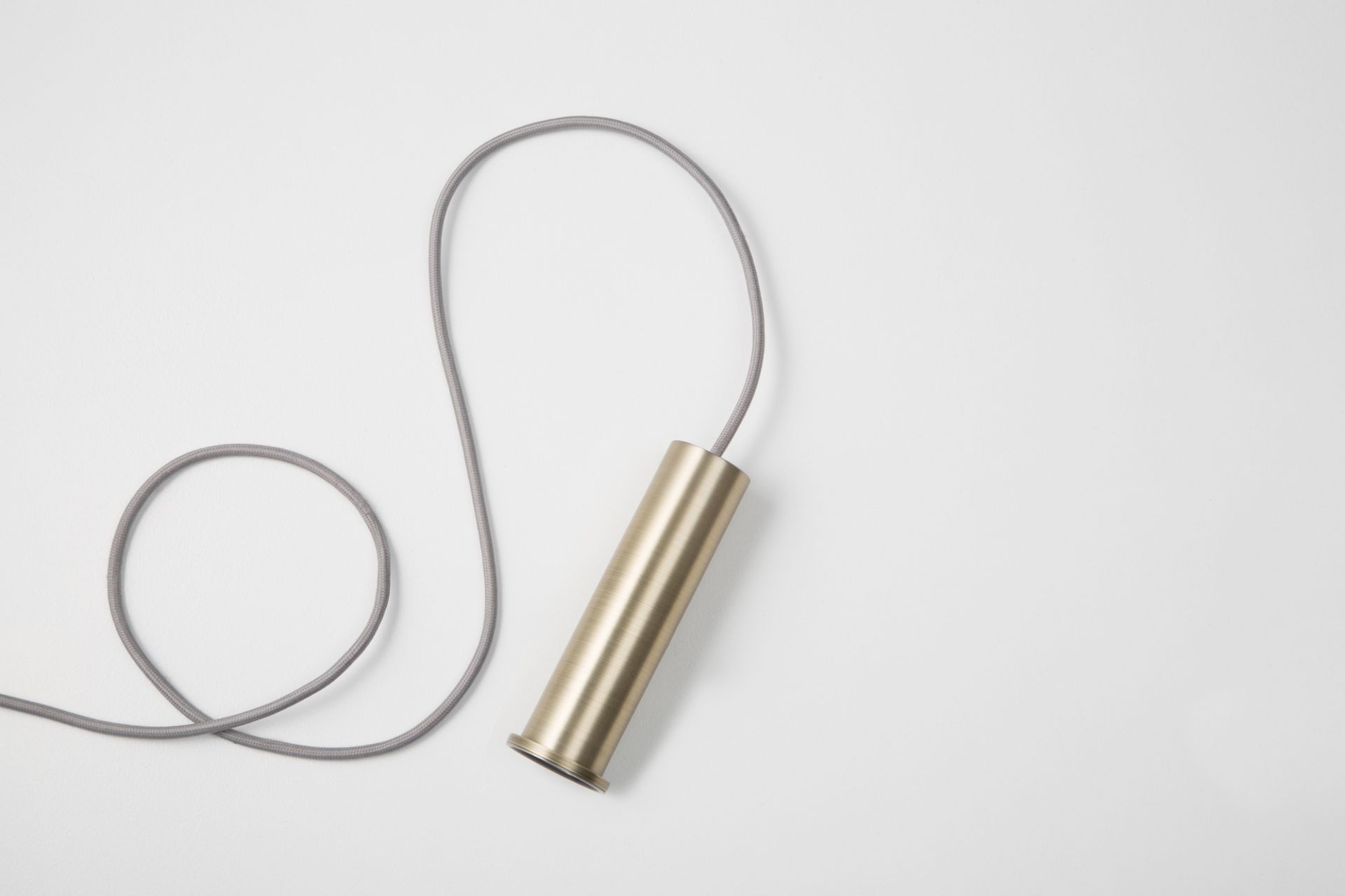 Ferm Living Collect Pendelleuchte in hochglänzendem Messing mit grauem Textilkabel auf weißem Hintergrund.