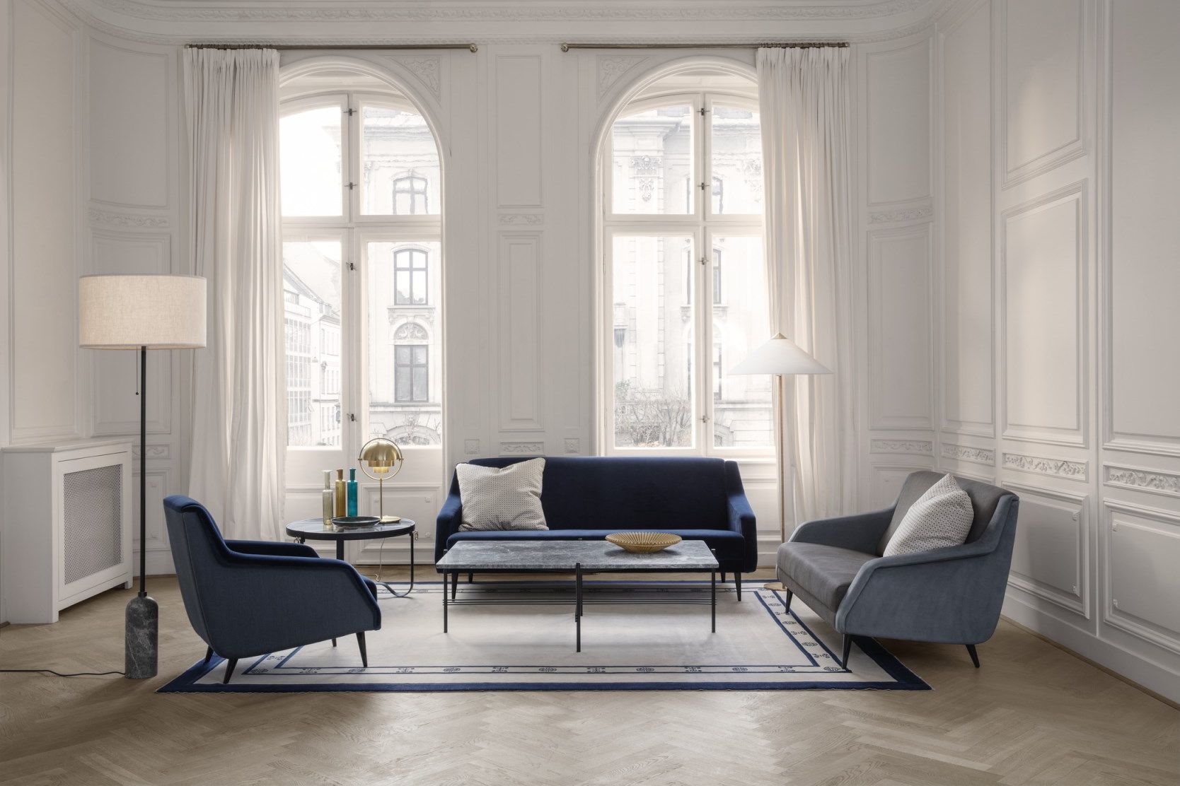 Wohnzimmer mit Gubi Adnet Couchtisch, schwarzem Leder, Sofa und Sesseln in Blau und Grau.